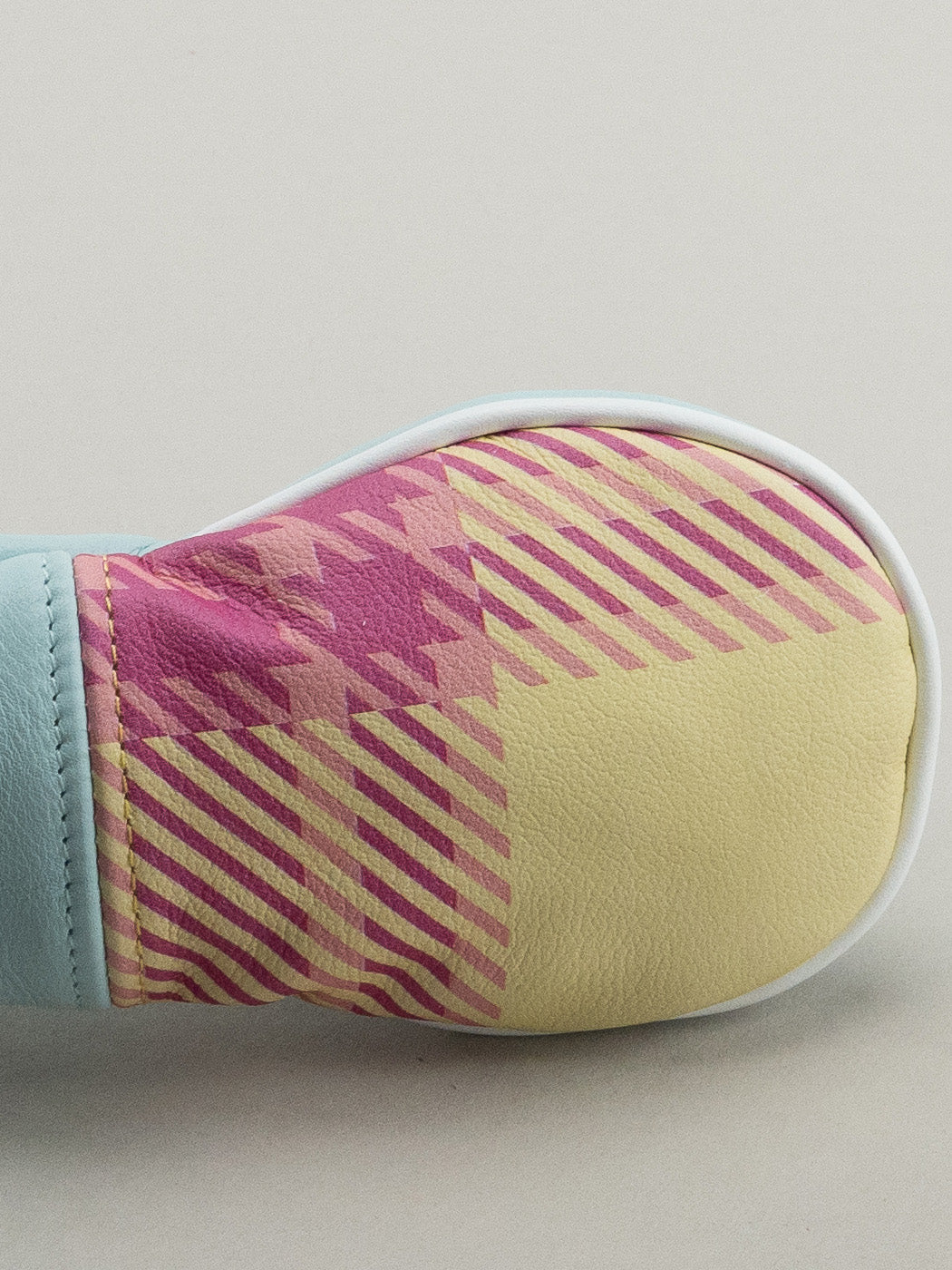 Close up of plaid on Golf club headcover made of pink, yellow and blue plaid with a blue leather base.