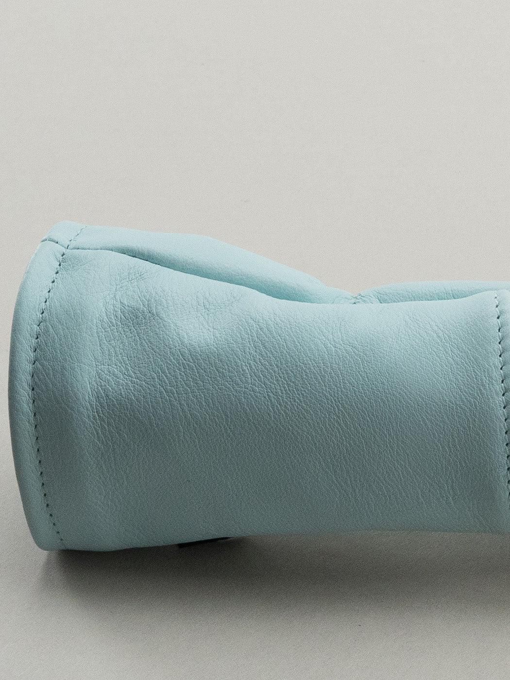 Close up of blue leather base on Golf club headcover made of pink, yellow and blue plaid with a blue leather base.