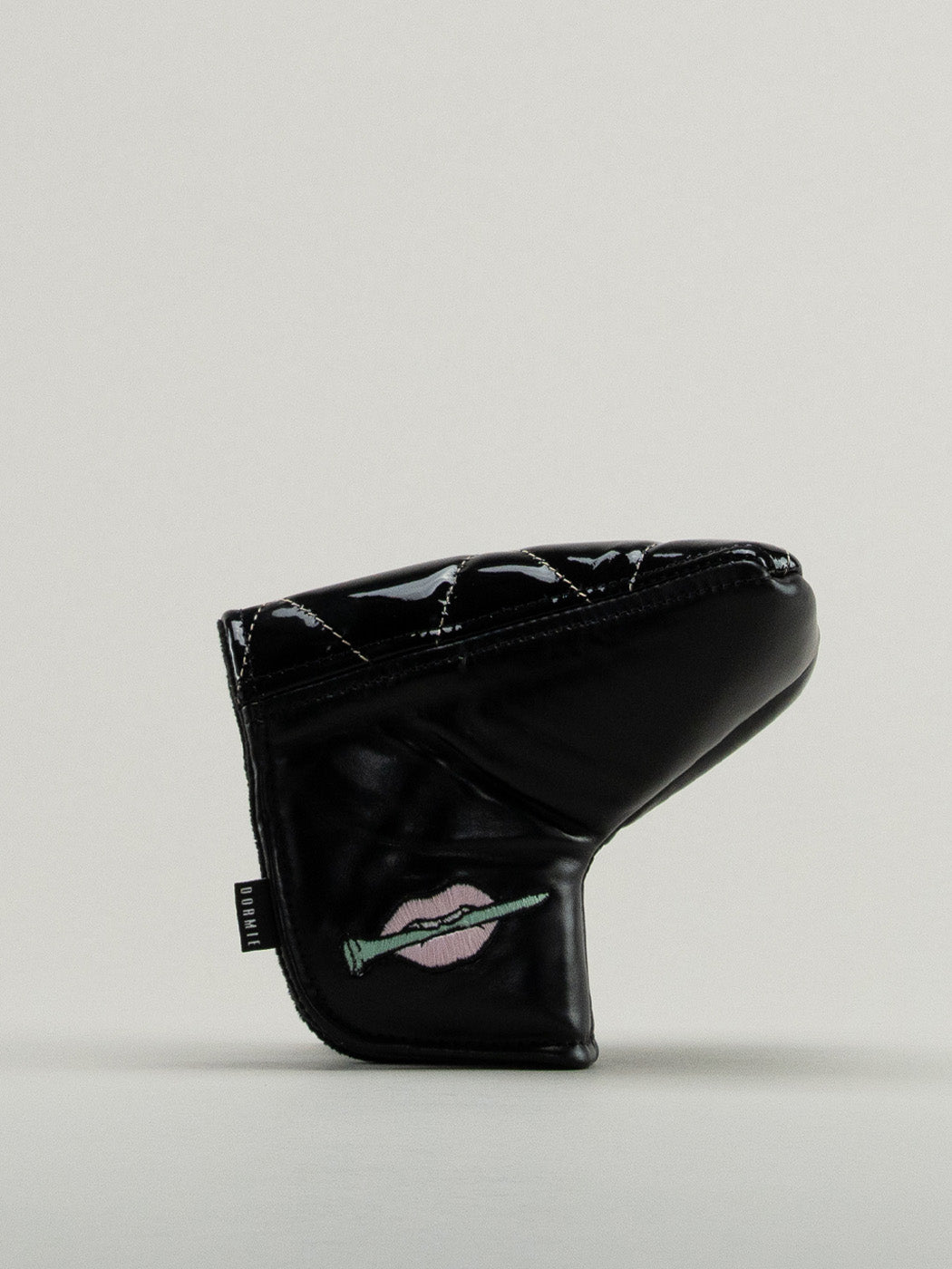 Black quilted leather golf headcover with small icon of embroidered lips clutching a golf tee.